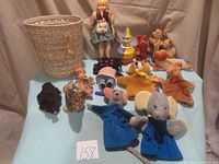 Full display of the vintage soft toys including the basket. The items shown include a wooden or wicker basket, several plush animals including a mouse and elephant in blue outfits, clown toy, and a vintage doll in cloth dress.