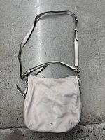 Full view of the light pink leather Kate Spade purse laid flat, showing adjustable strap and overall wear.