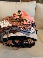 Pile of folded women's summer clothes showing a variety of colors and patterns including floral, coral, brown, and animal prints