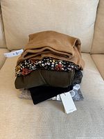 Stack of 6 folded women's winter clothing pieces including knit sweaters and mixed fabric items, some with tags visible