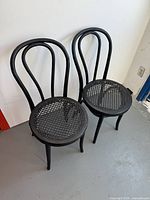 Pair of black bentwood cane chairs side by side showing seat and backrest design.