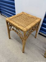 Front angle view of the small wicker side table showing woven square top and curved wicker legs with scroll design.