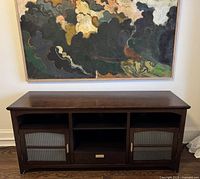 Front view of wooden TV media stand with ribbed glass doors and central drawer