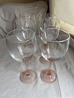 Front and top view of six clear bowl wine glasses with blush pink stems and bases arranged in two rows.