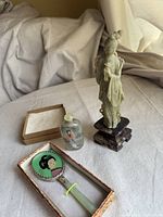 Overall view showing carved jade geisha figurine, glass snuff bottle, and jade handled mirror in box.