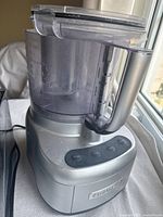 Silver Cuisinart food processor base and work bowl with buttons visible and feed tube open