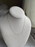 Full view of delicate gold necklace draped on display bust