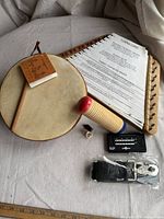 Top view of all items in the lot including ocean drum, shaker, tuning card, digital tuner, and strap.