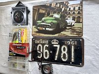 Complete view of the lot items including fishing tackle kit, decorative metal plaque, license plate, and compass.