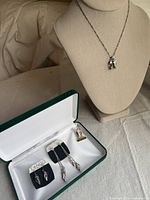 Tango inspired silver jewelry displayed on a bust and in a box, featuring necklace and earrings highlighting tango dance shoe charms.