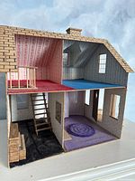 Front and interior view of wooden dollhouse showing two floors with wallpaper in various patterns and colors, stairs, and baby crib.