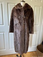 Full view of the vintage Simpsons full-length brown fur coat on a dress form, showing length and button closure.