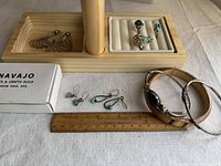 Overview of all jewelry items including earrings, rings, bracelets and Navajo box with ruler for scale