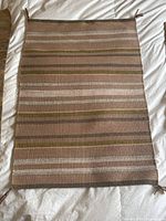 Full view of the vintage Navajo saddle blanket rug showing striped wool design with tassels at corners.
