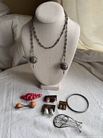 Full view of all jewelry items included in lot: Yemeni necklace, pairs of earrings, silver bangle, arrangement on white surface with natural light