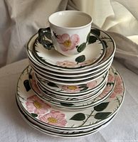 Stacked Wild Rose dinnerware set showing plates and a cup on top, with floral patterns.