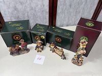 Four Boyds Bears figurines lined up with their original green and burgundy boxes behind them.