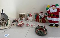 Full view of all items including ceramic church, multiple Santa figures, Liberty Bell plaque, votive holder, and wall hangers