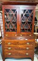 Full front view showing the mahogany secretary desk/bookcase with glass doors, drawers, and brass handles.