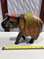 Side view of wooden hand painted carved elephant sculpture showing detailed colors and patterns, size about 9 inches.