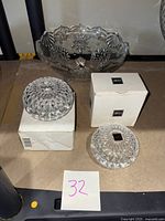 Two clear Liberty crystal trinket boxes with faceted, dome-shaped lids on their boxes, accompanied by a Mikasa snowflake patterned footed candy dish behind.