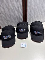 Six black Mobil 1 NASCAR official motor oil baseball caps arranged in two rows, front logo side visible. Caps feature structured crown, curved brim, and embroidered colorful logo on front.