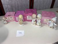 Four Precious Moments figurines displayed in front of their original pink boxes, showing the condition and packaging.