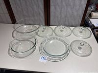 View of all items in the lot showing the large bowl, pie dish, smaller bowl, and four lids