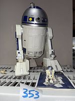 Front view of large R2D2 figure with mini R2D2 and instructions in front.