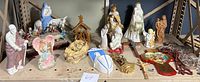 Shelf with assorted crosses, nativity scenes, angels including Joseph, Mary on donkey, angels with pink wings, and other figurines.
