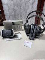 Full view of all three items: Sony wireless headphones with charging base, RCA 3.5-inch digital LED TV battery operated with user manual, and Sangean radio.
