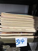 Side view showing stacked 11 vintage Playboy magazines in good condition, slight wear visible on edges.