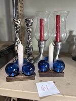 Full set of six candle stick holders shown grouped together on shelf, showing each type.