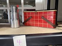 Side view showing the red cookie tin with brown foldable handles and stacked silver circular tins