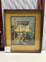 Full view of framed photo showing boat docked with wooden plank leading to it.