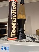 Photo of the lava lamp and Tootsie Roll bank side by side showing size comparison and condition.