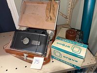 Polaroid Land Camera model 150 in leather case placed inside a larger box with additional boxed items including Argus pre-viewer