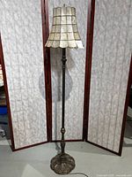 Full view of the vintage floor lamp showing the entire brass stem, base, and shell shade