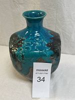 Full front view of pottery vase showing turquoise and teal iridescent glaze with brown earthy patches, smooth flared rim, approximately 9 inches tall.