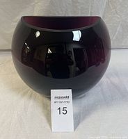 Round art glass bowl with deep plum interior and glossy black exterior shown from an angle
