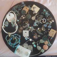 Flat lay of assorted blue and silver Bohemian style jewelry on black surface showing bracelets, earrings, and necklaces.