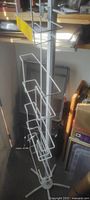 Full height view of the white metal literature magazine rack showing all seven angled wire compartments and the four-legged base.