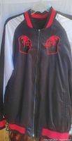 Front view of Star Wars themed black satin silk jacket with white sleeves and red trim. Red embroidered Darth Vader helmets on left and right chest.