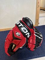 Pair of Easton SYN EQ3 hockey gloves showing red, black and white coloring and logo on cuff.