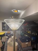 Close-up photo of the ribbed glass shade on the Mid Century Modern torchiere lamp, showing the translucent ribbed glass pattern and upper part of the brass-tone lamp fixture.