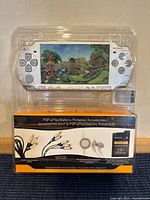 Front of blister packaging showing silver PSP console screen, accessories box and memory card