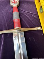 Close-up of sword blade showing Toledo logo and cross guard with leather wrapped handle and pommel with cross design
