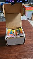 Open cardboard box displaying two visible 1989 O-Pee-Chee mini baseball cards at top of stack