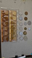 Overall view of plastic-sleeved 12-coin set and adjacent loose coins