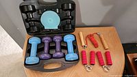Open carry case with four dumbbells, jump rope, hand grips visible
